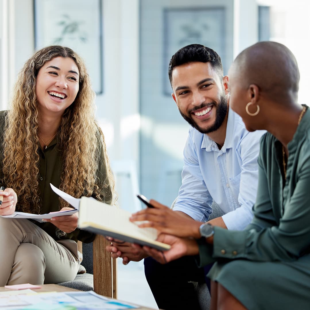 Three people smiling and looking at each other during a conversation